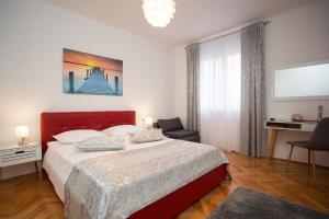 a bedroom with a large bed with a red headboard at Split Center Beautiful Apartment in Split