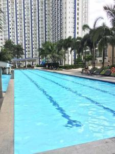 een groot blauw zwembad met gebouwen op de achtergrond bij Grass Residences Tower 5 in Manilla