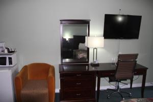 a desk in a hotel room with a mirror and a chair at Perth Plaza Inn & Suites in Perth