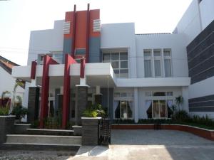 un gran edificio blanco con pilares rojos delante de él en Antika Hotel, en Rembang