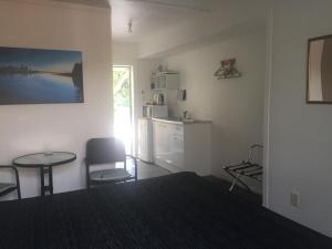 a bedroom with a table and chairs and a kitchen at Harbour View Motel in Coromandel Town