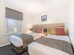 1 dormitorio con 2 camas y ventana en South Yarra Central Apartment Hotel, en Melbourne