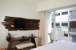 a bedroom with a desk and a tv on a wall at The Akmani Legian in Legian