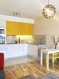 cocina con armarios blancos, mesa y sillas amarillas en ClickTheFlat Artistic Estate Apartment, en Varsovia