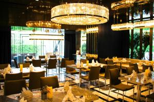 uma sala de jantar com mesas, cadeiras e lustres em Glam Habitat - SHA Extra Plus em Kamala Beach