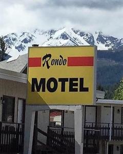 een motelbord voor een met sneeuw bedekte berg bij Rondo Motel in Golden