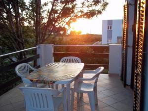 einen Tisch und Stühle auf einer Terrasse mit Blick auf den Sonnenuntergang in der Unterkunft Apartment Duskica - close to the sea in Petrcane