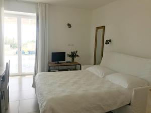 1 dormitorio con 1 cama y escritorio con TV en La Scibina, en Marina di Ragusa