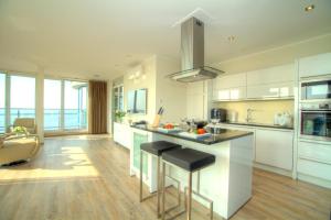 a kitchen with white cabinets and a counter with stools at Penthouse Müritzblick in Rechlin