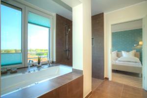 a bathroom with a tub and a bed and a window at Penthouse Müritzblick in Rechlin