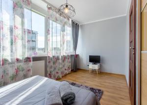 Schlafzimmer mit einem Bett, einem TV und Fenstern in der Unterkunft ClickTheFlat Golden Terraces Apart Rooms in Warschau
