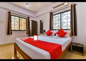 una camera con due letti con cuscini rossi e due finestre di Sweet AC Rooms near KFC Restaurant a Saligao