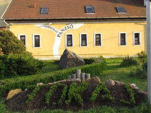 a yellow building with a sign on the side of it at Torkolat Panzió in Tokaj