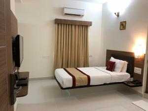 a hotel room with a bed and a television at Hotel Grand Bee Bangalore in Bangalore