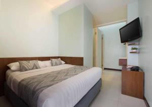 a bedroom with a bed and a flat screen tv at Tanaya Bed & Breakfast in Legian