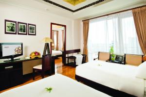 a hotel room with two beds and a television at Cherish Hue Hotel in Hue