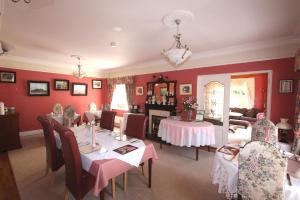 une salle à manger avec des murs rouges, des tables et des chaises dans l'établissement Maple Lodge, à Wexford