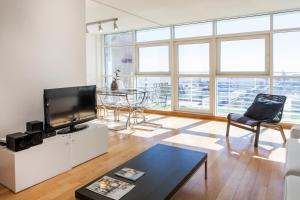 a living room with a television and a table at RENT4REST LISBON PARQUE DAS NAÇÕES 17Th FLOOR RIVER VIEW in Lisbon