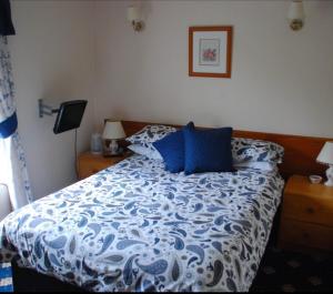 a bedroom with a bed with a blue and white comforter at Denmore Guest House in Aberdeen