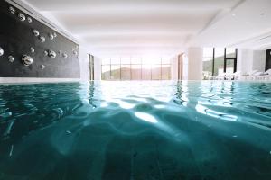 a swimming pool with blue water in a building at Chenot Palace Gabala in Gabala