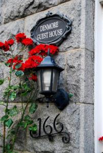 a street light on a stone wall with red flowers at Denmore Guest House in Aberdeen