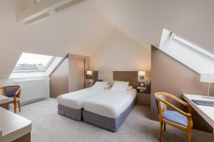 Cette chambre comprend un lit, un bureau et une fenêtre. dans l'établissement Hotel Restaurant Le Dauphin et Le Spa du Prieuré, à Caen