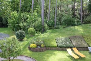 un jardin avec un banc et quelques buissons et arbres dans l'établissement La Tonnelle, à Hardelot-Plage