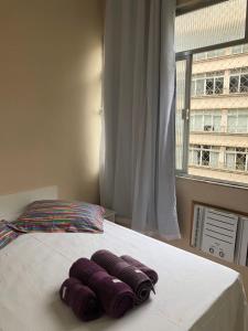1 cama con 3 toallas púrpuras y ventana en Studio Luxo em Copacabana, en Río de Janeiro
