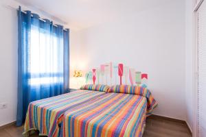 エル・プエルト・デ・サンタマリアにあるHoli-Rent Valdemar Vのベッドルーム1室(カラフルなストライプ毛布付きのベッド1台付)