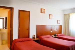 een hotelkamer met 2 bedden en rode lakens bij Hotel Os Caracoles in Pereiro de Aguiar