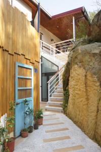 ein Haus mit einer blauen Tür und einer Treppe neben einem Felsen in der Unterkunft Heaven Bird B&B in Nanzhuang