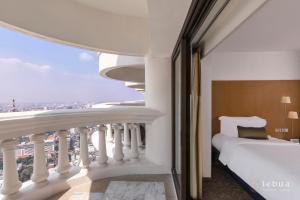 a hotel room with a bed and a balcony at Tower Club at lebua in Bangkok
