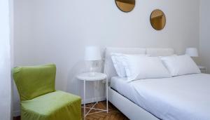 ein Schlafzimmer mit einem weißen Bett und einem grünen Stuhl in der Unterkunft Italianway-Nerino in Mailand