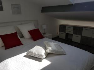 um quarto com uma cama branca com almofadas vermelhas e brancas em Mikado em La Gaude