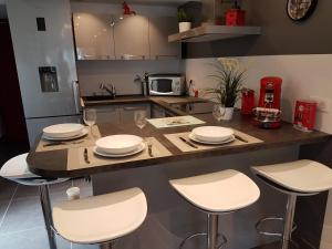 uma cozinha com uma mesa com placas e cadeiras brancas em Mikado em La Gaude