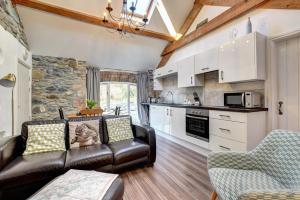 a living room with a leather couch and a kitchen at Beudy Menai in Llanddeiniolen