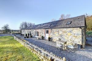a stone house with a stone wall around it at Beudy Menai in Llanddeiniolen