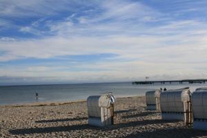 a row of beach chairs on a beach with a pier at Haus Antje in Scharbeutz