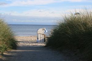 a beach chair sitting on the sand near the ocean at Haus Antje in Scharbeutz