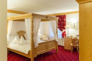 a bedroom with a canopy bed and a desk at Hotel Italia in Castello di Fiemme +51 photos