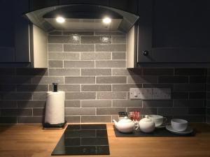 a kitchen with a brick wall and a counter with dishes at Bickfield Annexe in Ubley