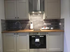 a kitchen with white cabinets and a sink at Bickfield Annexe in Ubley