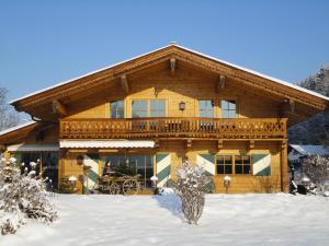 une cabane en rondins dans la neige avec un balcon dans l'établissement Appartement Ölberg, à Kitzbühel