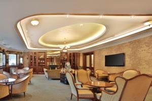 a hotel lobby with tables and chairs and a flat screen tv at Retro Riverside Wellness Resort in Karlovy Vary