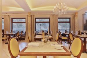 a dining room with tables and chairs and a chandelier at Retro Riverside Wellness Resort in Karlovy Vary