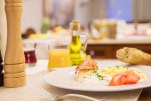 a plate of food on a table with a glass of orange juice at Retro Riverside Wellness Resort in Karlovy Vary