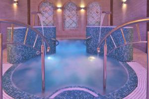 a pool of water in a room with chairs at Retro Riverside Wellness Resort in Karlovy Vary