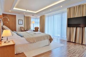 a bedroom with a large bed and a flat screen tv at Retro Riverside Wellness Resort in Karlovy Vary