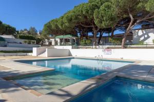a swimming pool with blue water and trees at FLH Albufeira Açoteias Apartment in Albufeira