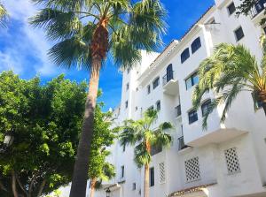 biały budynek z palmami przed nim w obiekcie Puerto Banus Beach w Marbelli